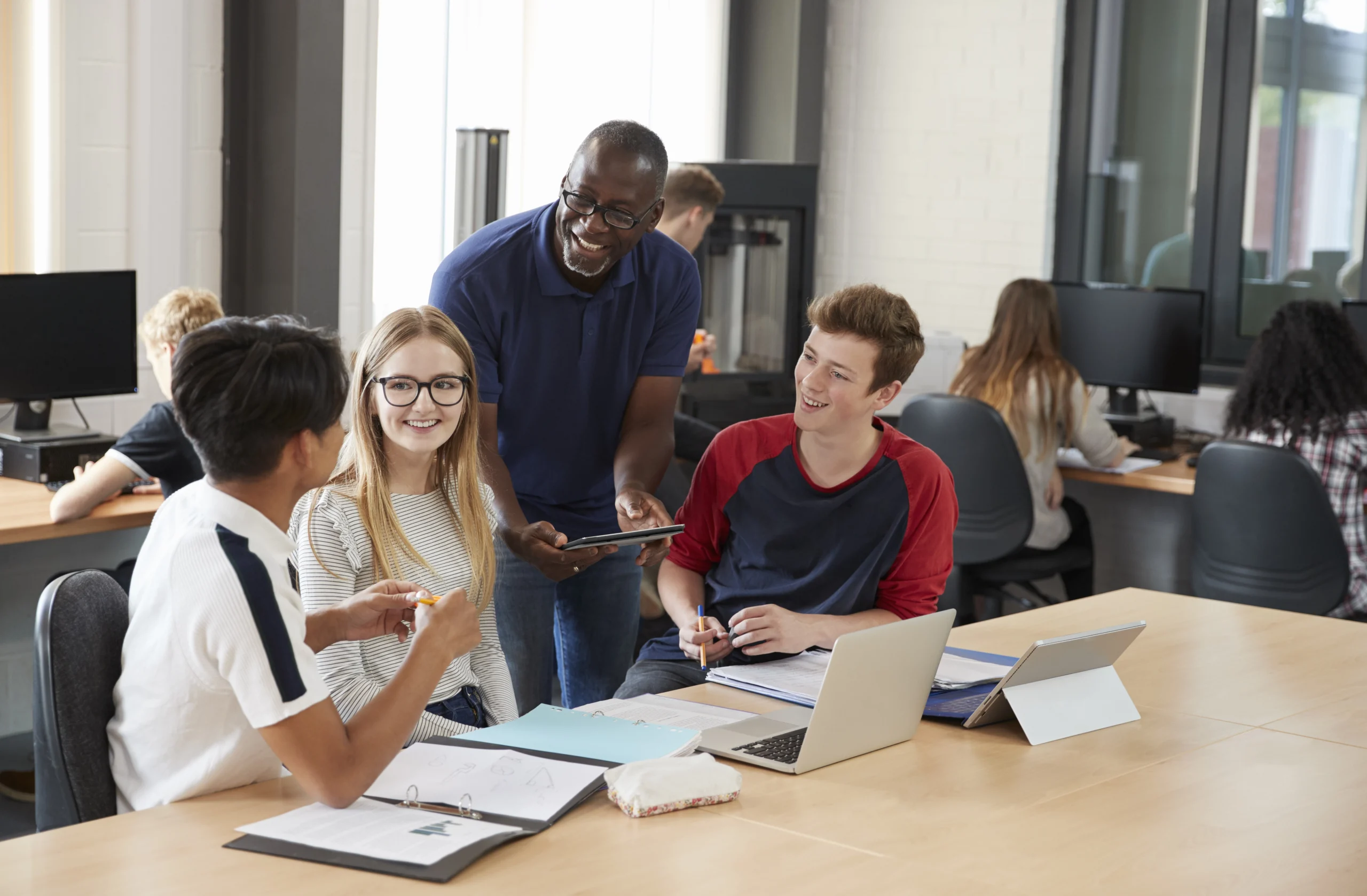 Three interns with an older man and some other students in the background.