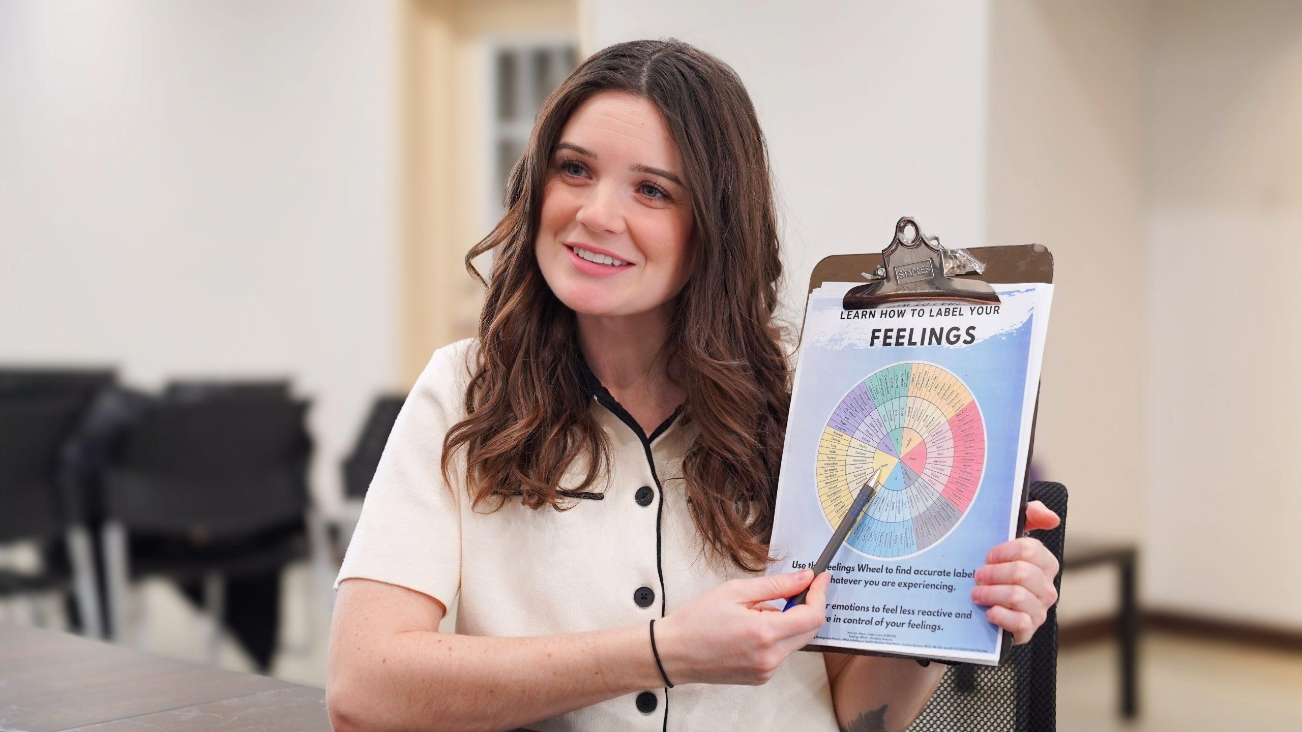 Kylie showing a feelings chart to a client