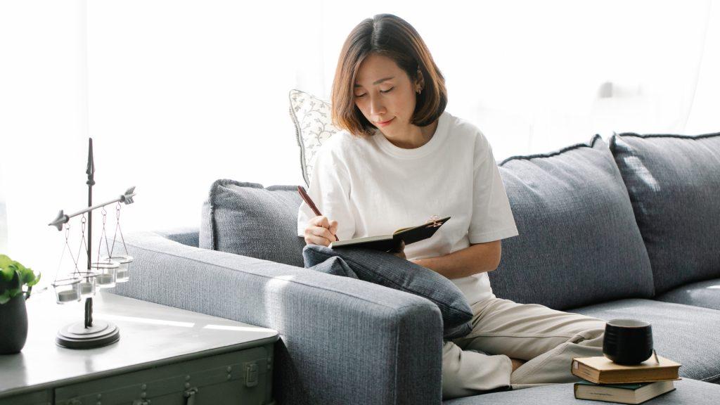 Woman Sitting on Sofa Writing in Journal