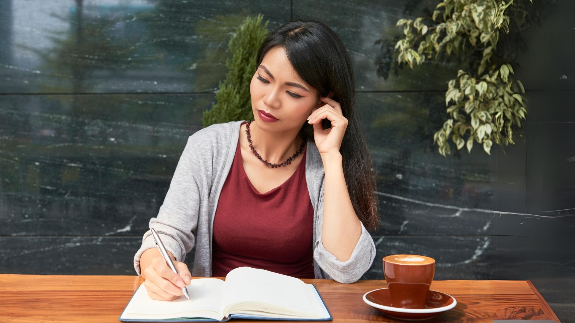Young Woman Journaling at Café Table with Coffee