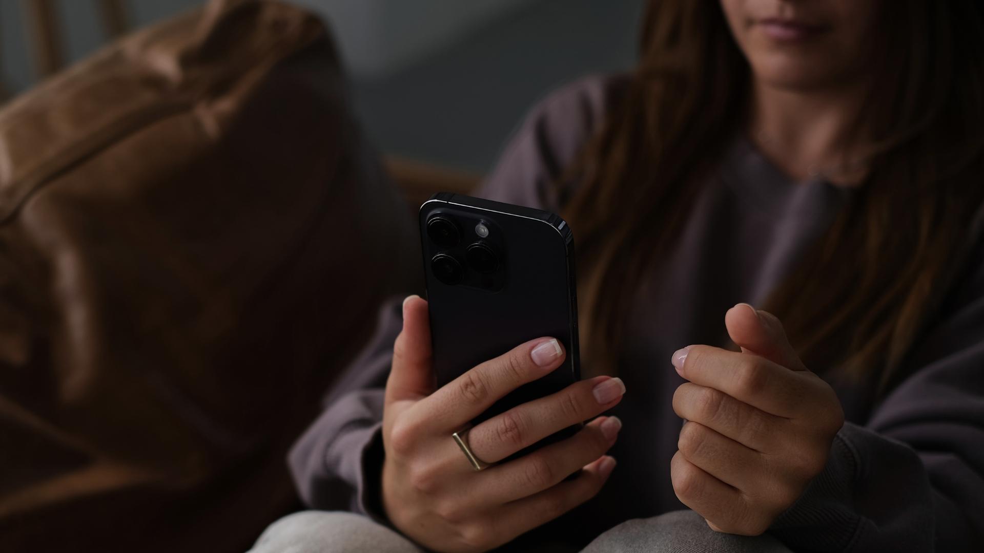 This image captures a silent moment with a woman holding her phone—reflecting how AI monitors our digital behavior for hidden signs of mental health struggles.